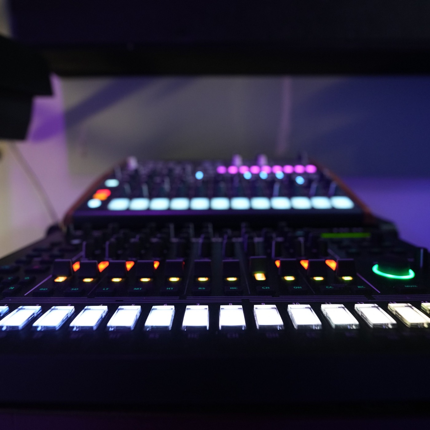 Close on a lit drum machine, its pads and controls glowing on the studio desk.
